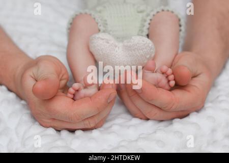 Beine eines neugeborenen Babys in den Händen des Vaters. Das Konzept der elterlichen Liebe und einer glücklichen Familie. Stockfoto