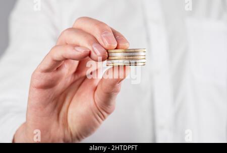 Geschäftsmann Hand Nahaufnahme hält Münzen Stapel. Geld- und Einkommenskonzept. Hochwertige Fotos Stockfoto
