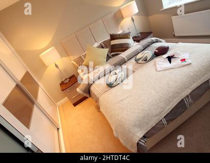 Modernes Schlafzimmer für Jungen in einem neu erbauten Haus, Rugby-Thema, Bettüberwurf, beigefarbenes neutrales Farbschema, hohe gepolsterte Kopfteile, Rugby-Kugeln, Schlafzimmer für Jungen, Stockfoto