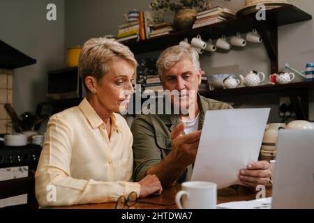 Kaukasisches Seniorenpaar, das von zu Hause aus arbeitet und Rechnungen und Zahlungen ansieht Stockfoto