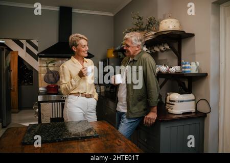 Kaukasisches älteres Paar, das in der Küche plaudert und das Morgenlicht genießt Stockfoto
