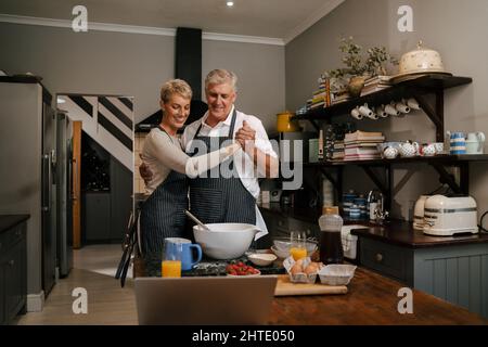 Liebevolles kaukasisches Seniorenpaar, das in der Küche tanzt Stockfoto