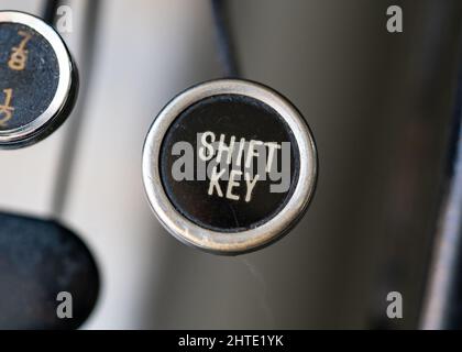 Retro Vintage Schreibmaschine runde Schlüssel Nahaufnahme mit goldfarbenen Shift-Taste auf schwarzem Hintergrund. Stockfoto