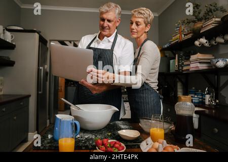 kaukasisches Seniorenpaar sucht Rezept mit Laptop Stockfoto
