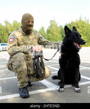 Soldat der KORD Einheit Ukrainischer SWAT in Uniform und sein Polizeihund auf dem Boden sitzend Stockfoto