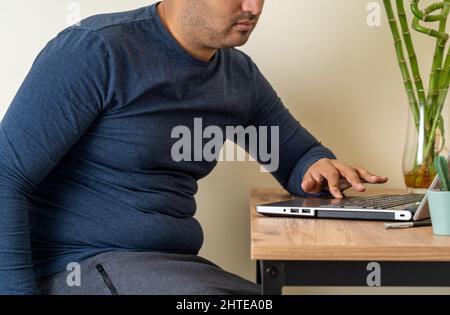 Seitenansicht Foto des Home Office-Mitarbeiters mit fettem Bauch. Konzept von Fett oder Adipositas aufgrund von Remote-Arbeit. Stockfoto