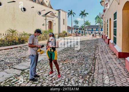 Erwachsene asiatische männliche Touristen kaufen frische Bananen von lokalen schwarzen Frau auf der Straße in Trinidad, Kuba Stockfoto