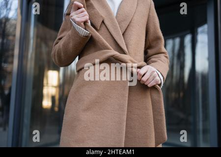 Die Frau bindet einen Gürtel auf einen Mantel Stockfoto