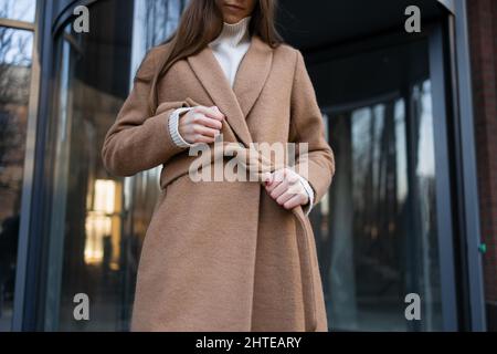 Mädchen bindet einen Gürtel auf einen Mantel Stockfoto