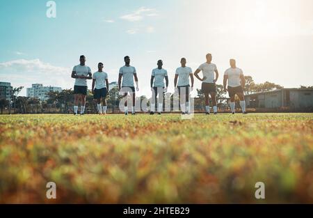 Teamarbeit führt zu großem Erfolg auf dem Feld. Rückansicht einer Gruppe junger Rugby-Spieler, die auf einem Feld stehen. Stockfoto