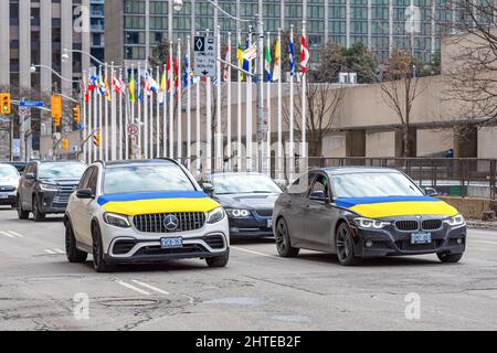 Toronto, Kanada - 27. Februar 2022: Autos mit ukrainischer Flagge fahren in den Straßen von Toronto. Die Flaggen aller kanadischen Provinzen und Territorien Stockfoto