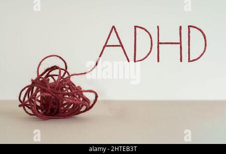 Knoten geschrieben „ADHS“ durch Verwendung von roten Seil. Konzept der Aufmerksamkeitsdefizit-Hyperaktivitätsstörung und der psychischen Störung im frühen Alter auf Konzentration. Stockfoto