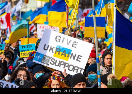 Toronto, Kanada - 27. Februar 2022: Eine Schar von Demonstranten marschiert in der Bay Street mit Schildern und ukrainischen Flaggen. Die Kundgebung zur Unterstützung der Ukraine A Stockfoto