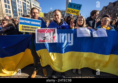 The Dam, Amsterdam, Niederlande. Sonntag, 27.. Februar 2022. Rund 15,000 Demonstranten versammelten sich heute Nachmittag am Amsterdamer Staudamm, um Solidarität mit der ukrainischen Bevölkerung zu zeigen und die russische Invasion von Präsident Putin zu verhindern. Schätzungsweise 100,000 Menschen protestierten in Europa und zahlreiche Russen schlossen sich den Demonstranten am Staudamm an, um Solidarität zu zeigen. Auch in den niederländischen Städten Groningen und Heerlen gingen Menschen auf die Straße. Bildunterschrift: Demonstranten mit Transparenten, Plakaten der Nationalflagge der Ukraine, auf dem Damm in Amsterdam, während des 15. Nachmittags. Stockfoto