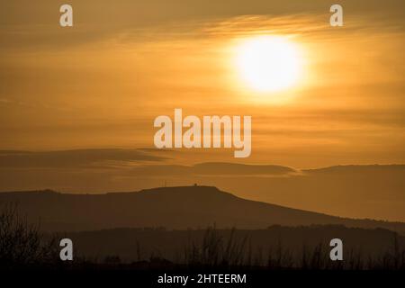 Titterstone Clee Hill, Großbritannien. 27.. Februar 2022. Wetter in Großbritannien: An einem sonnigen, trockenen Tag geht die Sonne über dem Titterstone Clee Hill in Shropshire unter. Auf dem Hügel befindet sich die Radarstation der National Air Traffic Services. Als die Radarstation 1941 zum ersten Mal gebaut wurde, wurde sie als oberste Sicherheitsstufe eingestuft und befindet sich auf 533m Metern über dem Meeresspiegel und überwacht alle Flugzeuge in einem Radius von 100 Meilen. Kredit: Lee Hudson Stockfoto