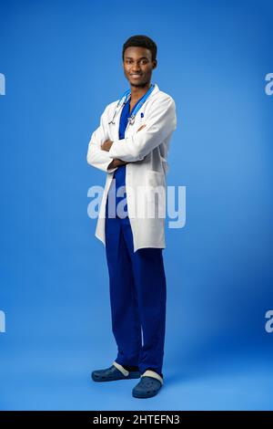 Selbstbewusster schwarzer Arzt posiert über blauem Studiohintergrund. Stockfoto