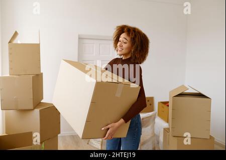 Müde junge Frau, die zwischen Kartons steht Stockfoto