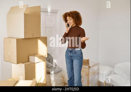 Junge Frau telefoniert zwischen Kartons Stockfoto