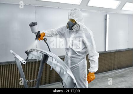 Techniker in Sicherheitskleidung, der Autolack sprüht Stockfoto