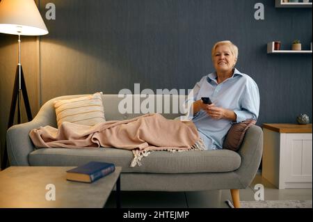 Reife Frau eingewickelt in Decke Fernsehen Stockfoto
