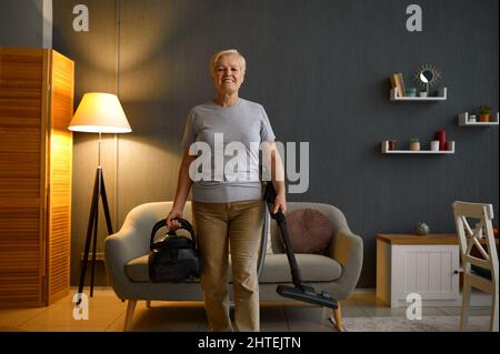 Glückliche ältere Frau, die das Haus putzt Stockfoto