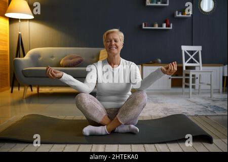 Reife Frau, die Yoga in Lotushaltung praktiziert Stockfoto