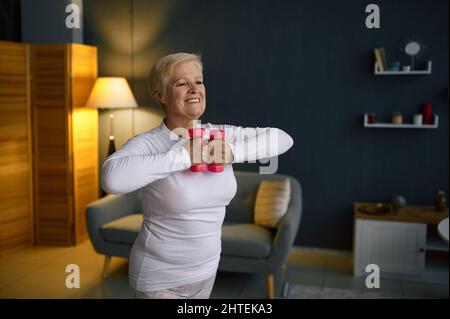 Ältere Frau, die zu Hause mit Kurzhanteln trainiert Stockfoto