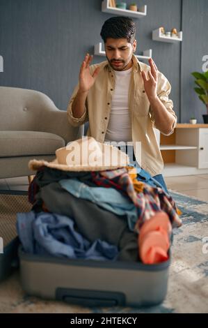 Mann, der versucht, Kleidung in den Koffer zu passen Stockfoto