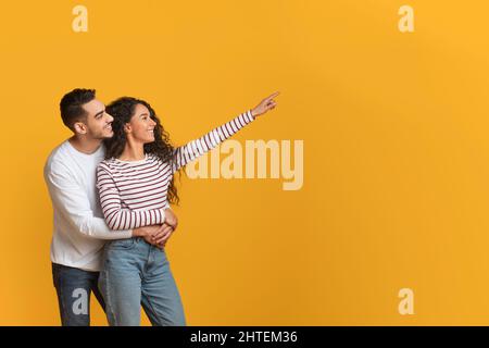 Familienangebot. Glückliche Arabische Ehegatten Umarmen Und Zeigen Beiseite Auf Copy Space Stockfoto