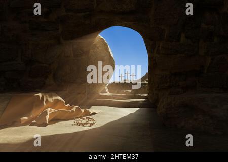 Leeres Grab von Jesus Christus. Verlassene Grabtuch und Dornenkrone auf dem Boden. Licht ergießt sich in die Höhle. 3D Abbildung Stockfoto