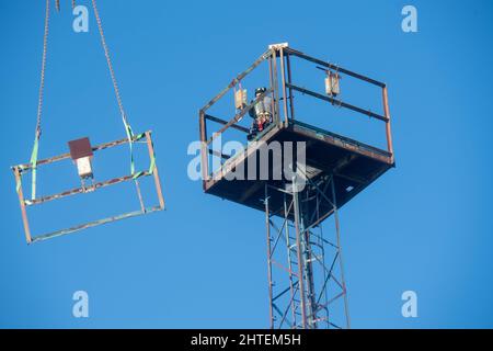 Stralsund, Deutschland. 28.. Februar 2022. Arbeiter demontieren einen Lichtmast im Hafen von Stralsund. Der alte Gittermast muss demontiert werden, da er die neuen Windlaststandards nicht mehr erfüllt. Außerdem konnte aufgrund der technischen Bedingungen keine neue Beleuchtung mehr am bestehenden Mast angebracht werden. Der Mast ist als Hafenanlage gelistet und wird durch einen neuen Gittermast ersetzt. Quelle: Stefan Sauer/dpa/Alamy Live News Stockfoto