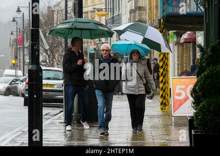 Bridport, Dorset, Großbritannien. 28.. Februar 2022. Wetter in Großbritannien. Bei dem starken Regen in Bridport in Dorset, an einem nassen Nachmittag am letzten Tag des meteorologischen Winters, halten sich die Käufer unter Regenschirmen auf dem Bürgersteig zurück. Bildnachweis: Graham Hunt/Alamy Live News Stockfoto