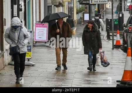 Bridport, Dorset, Großbritannien. 28.. Februar 2022. Wetter in Großbritannien. Bei dem starken Regen in Bridport in Dorset, an einem nassen Nachmittag am letzten Tag des meteorologischen Winters, halten sich die Käufer unter Regenschirmen auf dem Bürgersteig zurück. Bildnachweis: Graham Hunt/Alamy Live News Stockfoto