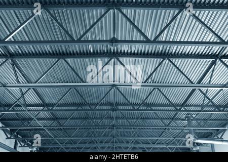 Dach oder Metalldecke von Industriegebäuden. Innenansicht. Von unten nach oben. Neues Gebäude. Metallträger und verzinkte Bleche. Industriedach. Hintergrund. Stockfoto