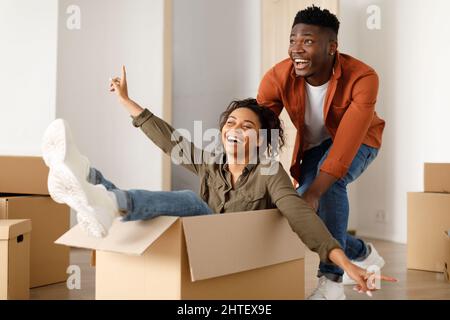 Afrikanischer Ehemann, Die Frau In Der Umzugskiste In Einem Neuen Zuhause Reitet Stockfoto