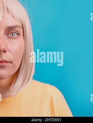 Nahaufnahme der traurigen kaukasischen 30s Frau trägt gelben Pullover Look Kamera isoliert auf blauem Hintergrund Studio. Stockfoto