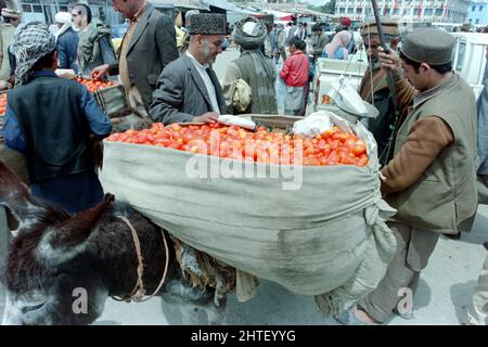 KABUL, AFGHANISTAN. 28.. April 1988. Ein afghanischer Gemüseverkäufer verkauft frische Tomaten vom Rücken seines Esels auf dem Hauptmarkt am 28. April 1988 in Kabul, Afghanistan. Das sowjetische Militär wird am 15.. Mai mit dem Rückzug aus Afghanistan beginnen. Stockfoto