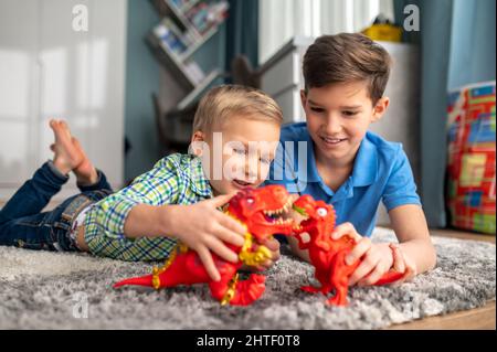 Kinder spielen Geschichten mit Spielzeug-Dinosauriern Stockfoto