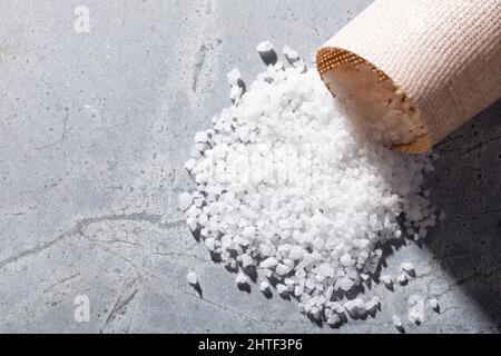 Nahaufnahme des Salzes aus weißem Stein, der aus dem Korbbehälter auf dem Tisch mit leerem Raum austreten kann Stockfoto