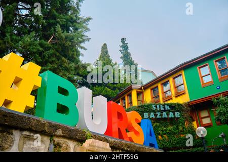 29.03.2021. Bursa.Türkei. Niedrige Winkel Buchstaben von 'Bursa', alte ottomanische Architektur Häuser und grüne Mausoleum Hintergrund lokalen Namen ist yesil Turbe. Stockfoto