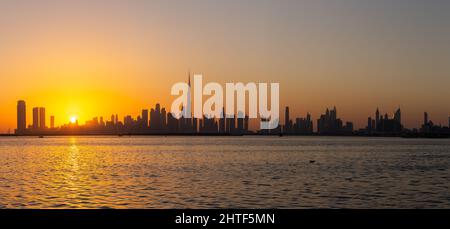 Panorama der Skyline von Dubai Downtown während des Sonnenuntergangs von der Hafenpromenade des Dubai Creek aus gesehen. Stockfoto