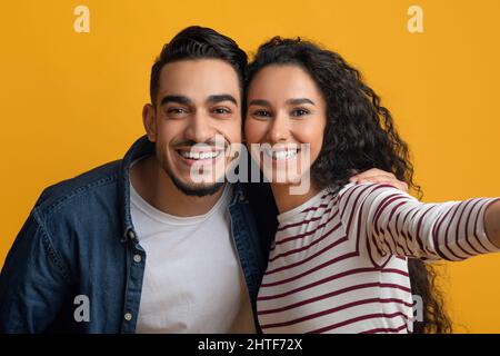 Fröhliches junges Paar aus dem Nahen Osten, das zusammen Selfie macht, POV Shot Stockfoto