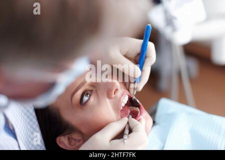 Patient besucht Zahnarzt. Aus der Sicht eines Zahnarztes, der die Zähne des Patienten überprüft. Stockfoto