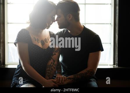 Ich möchte Euch wirklich küssen. Aufnahme eines liebevollen jungen Paares, das an einem Fenster sitzt. Stockfoto