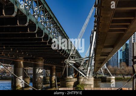 Ein Blick auf die Unterseite der Hungerford Bridge und eine der Golden Jubilee Bridges, die die Themse in London überspannt Stockfoto