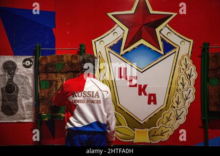 Region Moskau, Russland. 26.. Februar 2022 Ein Mann wirft Messer auf Ziele vor dem Hintergrund des Emblems des Sportvereins CSKA in einem Museum auf dem Territorium des militärisch-patriotischen Parks Patriot in der Region Moskau, das dem Vaterlandsverteidiger gewidmet ist. Die Inschrift lautet „CSKA“ Stockfoto