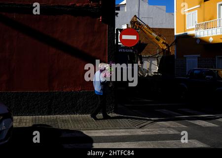 Ältere Frau mit einem Blumenstrauß in einer Seitenstraße in Playa San Juan, Teneriffa, Kanarische Inseln, Spanien Stockfoto