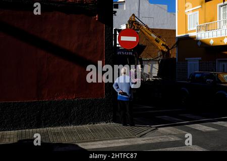 Ältere Frau mit einem Blumenstrauß in einer Seitenstraße in Playa San Juan, Teneriffa, Kanarische Inseln, Spanien Stockfoto