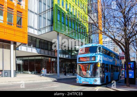 Ein blauer Bus, der an einer Bushaltestelle vor den modernen Bürogebäuden im Central Saint Giles-Viertel in London, Großbritannien, geparkt ist Stockfoto