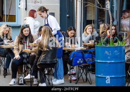 Menschen, die draußen in einem Café in Neal's Yard in der Nähe von Covent Garden in London, Großbritannien, essen. Stockfoto